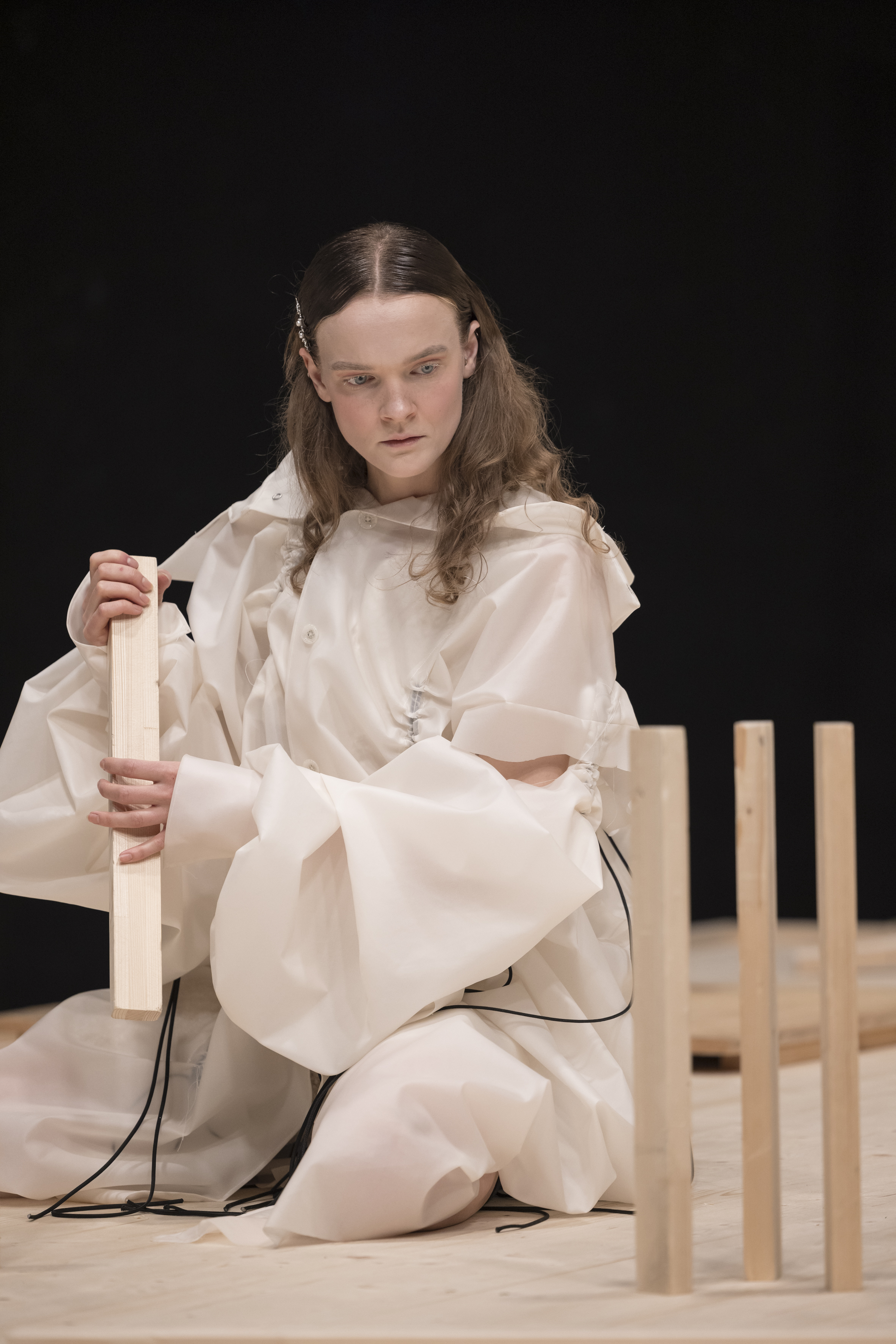 Darsteller:in von Kaspar errichtet eine einfache Konstruktion aus Holzlatten