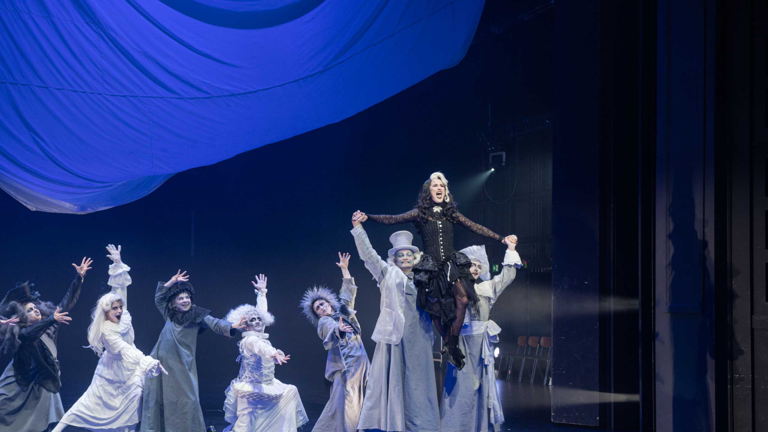 Produktionsbild Addams Family, Tanzreihe mit Morticia Addams auf den Schultern ihrer Ahnen