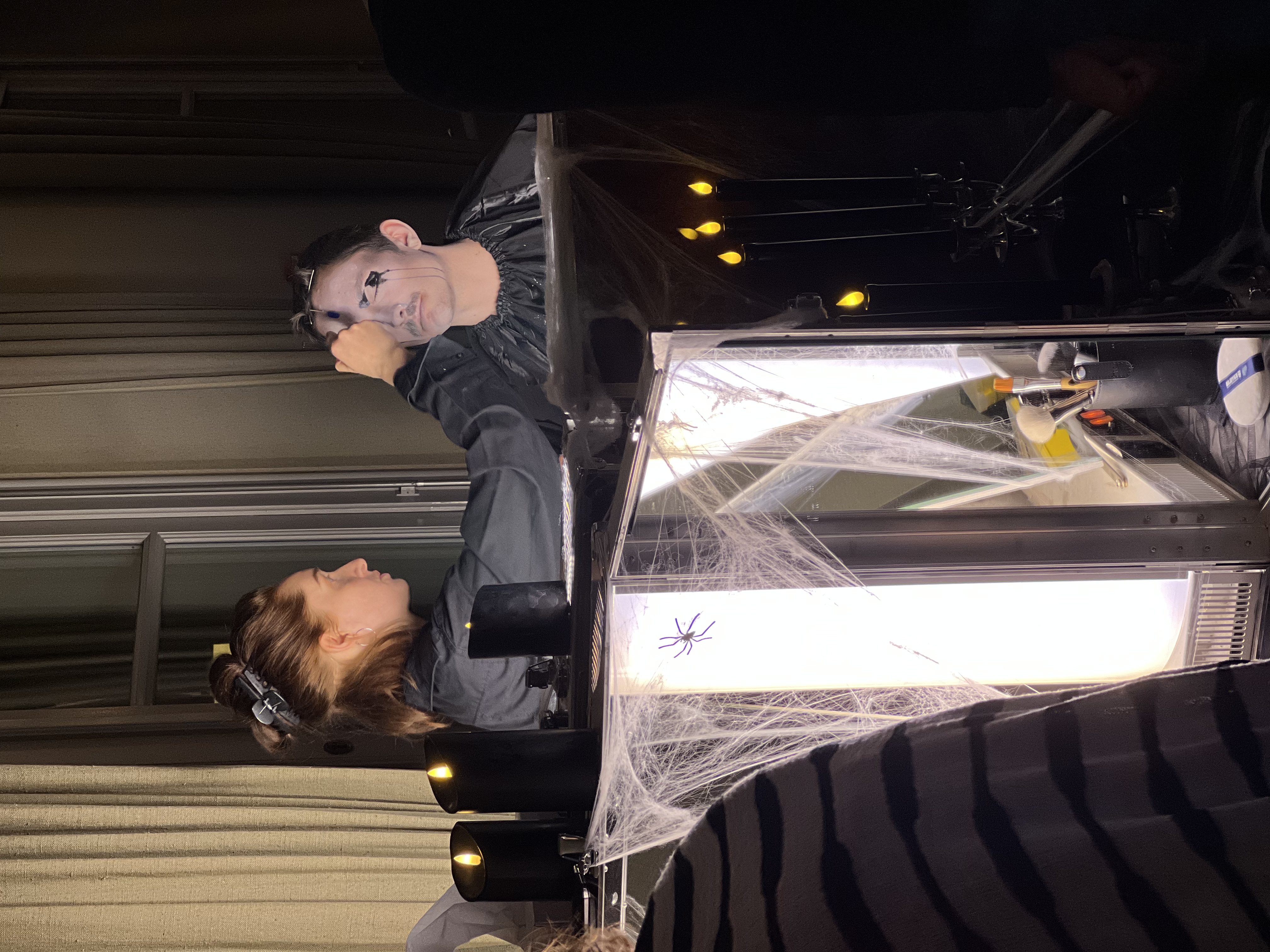 Studierende:r Floyd Clemens wird von Studierende:r Sophia Petermann als Addams Ahne geschminkt