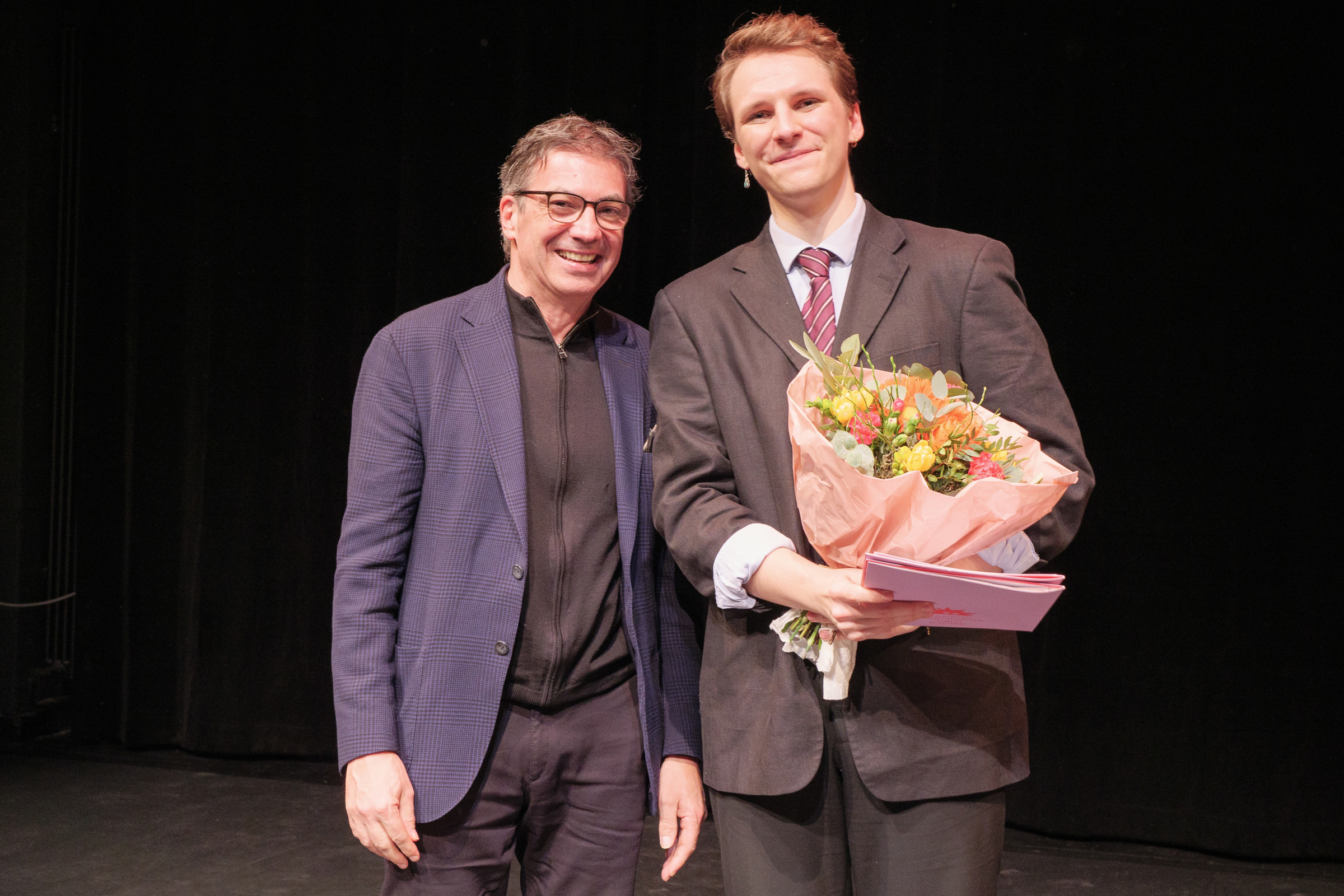 Dr. Helmut Hess von der Richard Stury Stiftung mit Thomas Siedhoff Preisträger 2026 Tillmann Schmuhl, der einen großen Blumenstrauß in der Hand hält