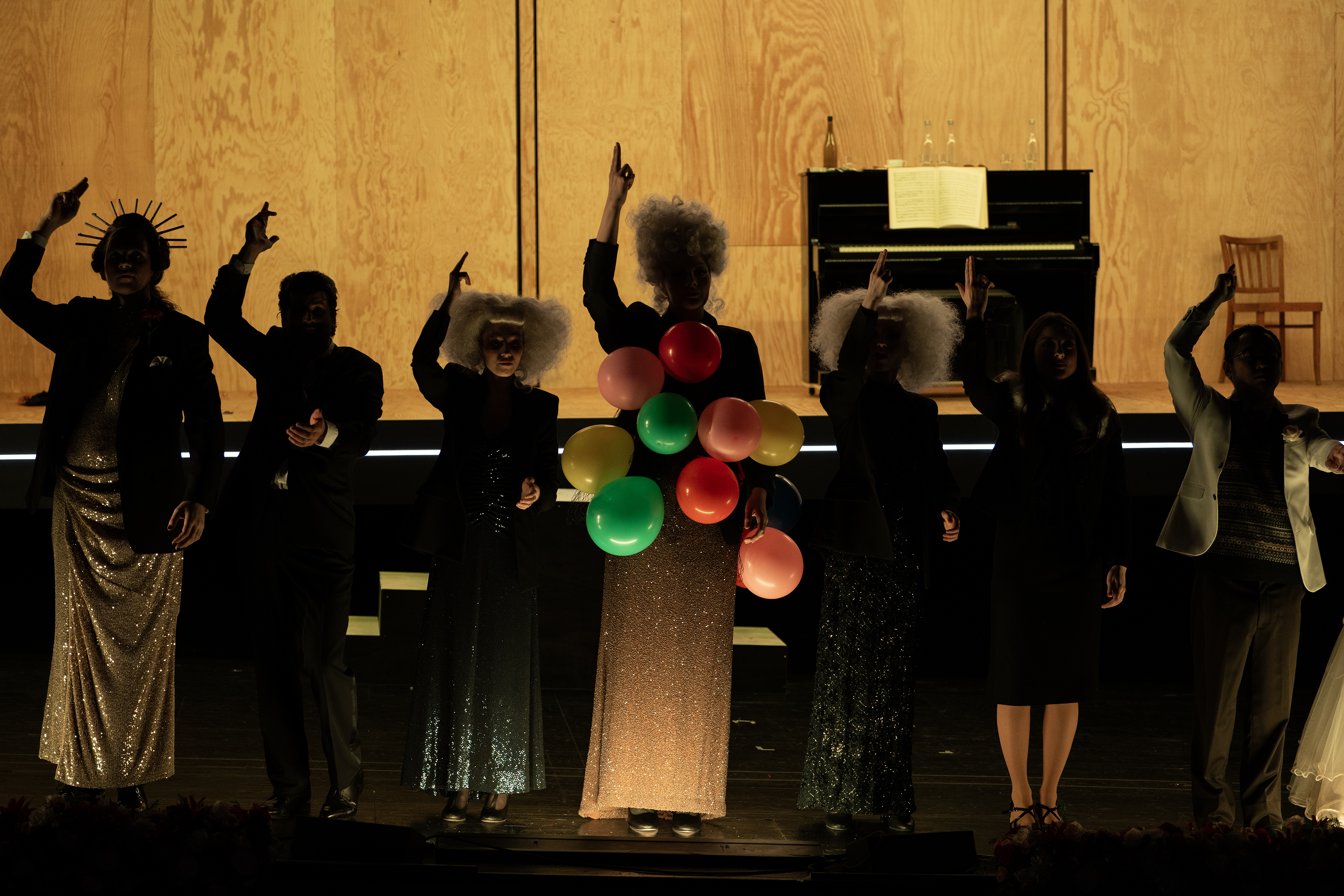 Die Silhouetten von sieben Personen, alle halten ihren ausgestreckten Zeigefinger in die Luft, eine Person trägt viele bunte Luftballons an ihrem Kleid