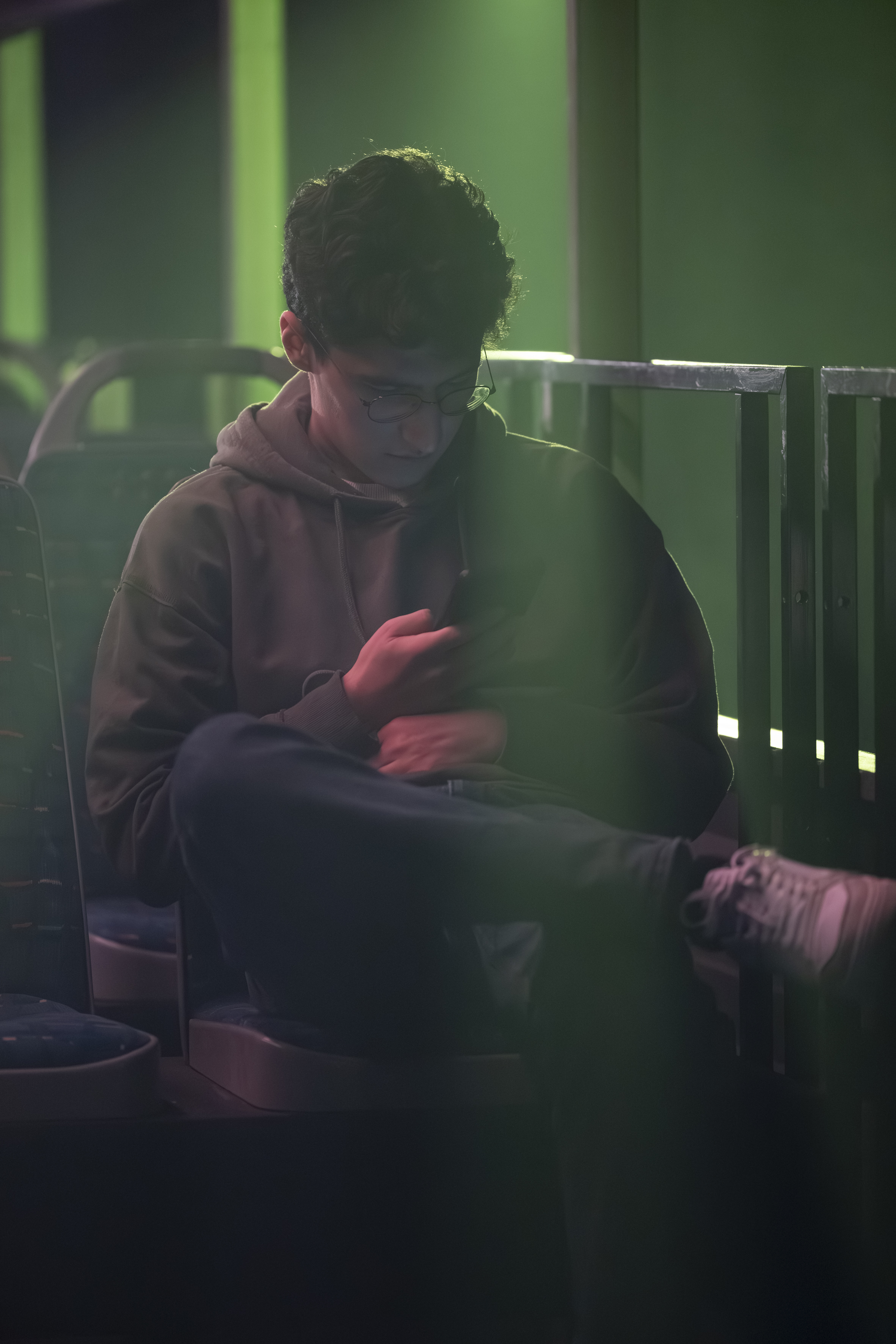 Eine Figur, sitzend im Bus, mit überschlagenen Beinen, schaut auf ihr Handy.