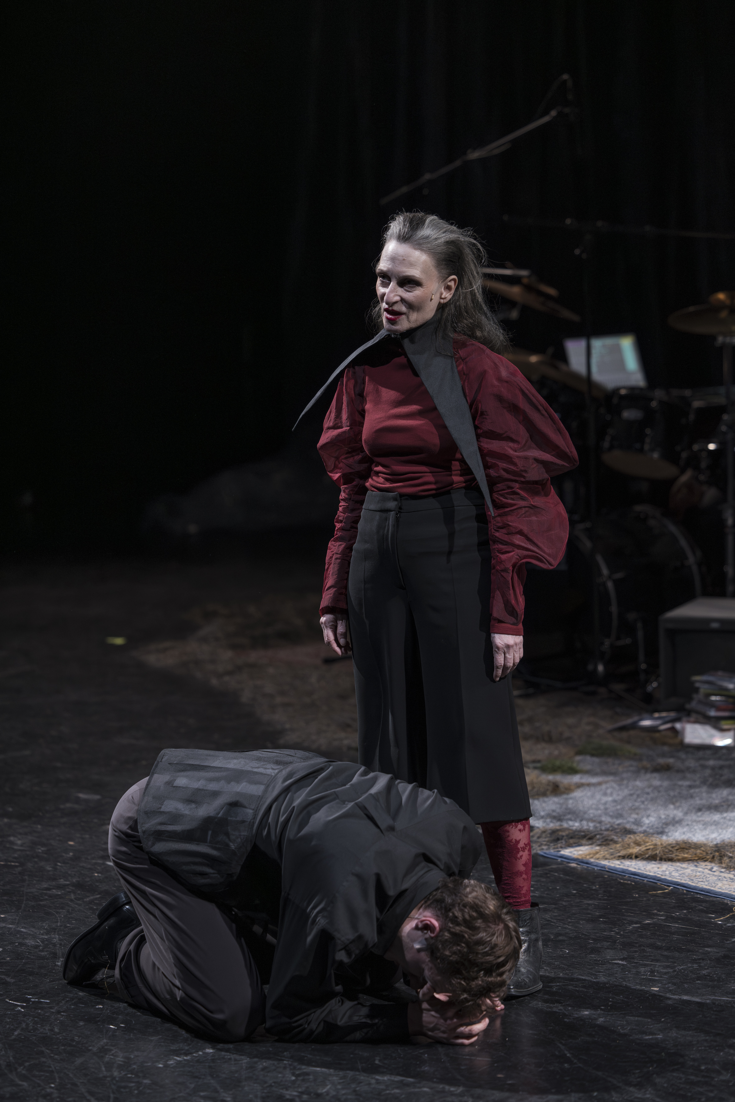 Eine Frau steht aufrecht, ein Mann kniet vor ihren Füßen mit gesenktem Kopf