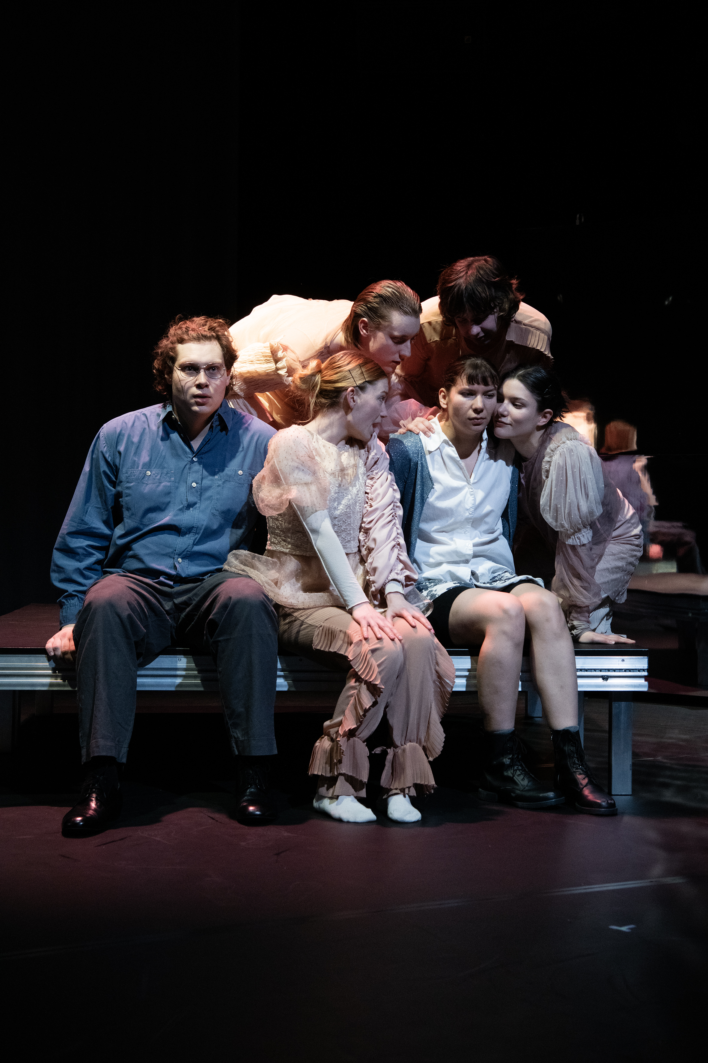 Sechs Personen sitzend, vier reden auf eine Frau ein, ein Mann sitzt links mit starrem Blick Richtung Kamera