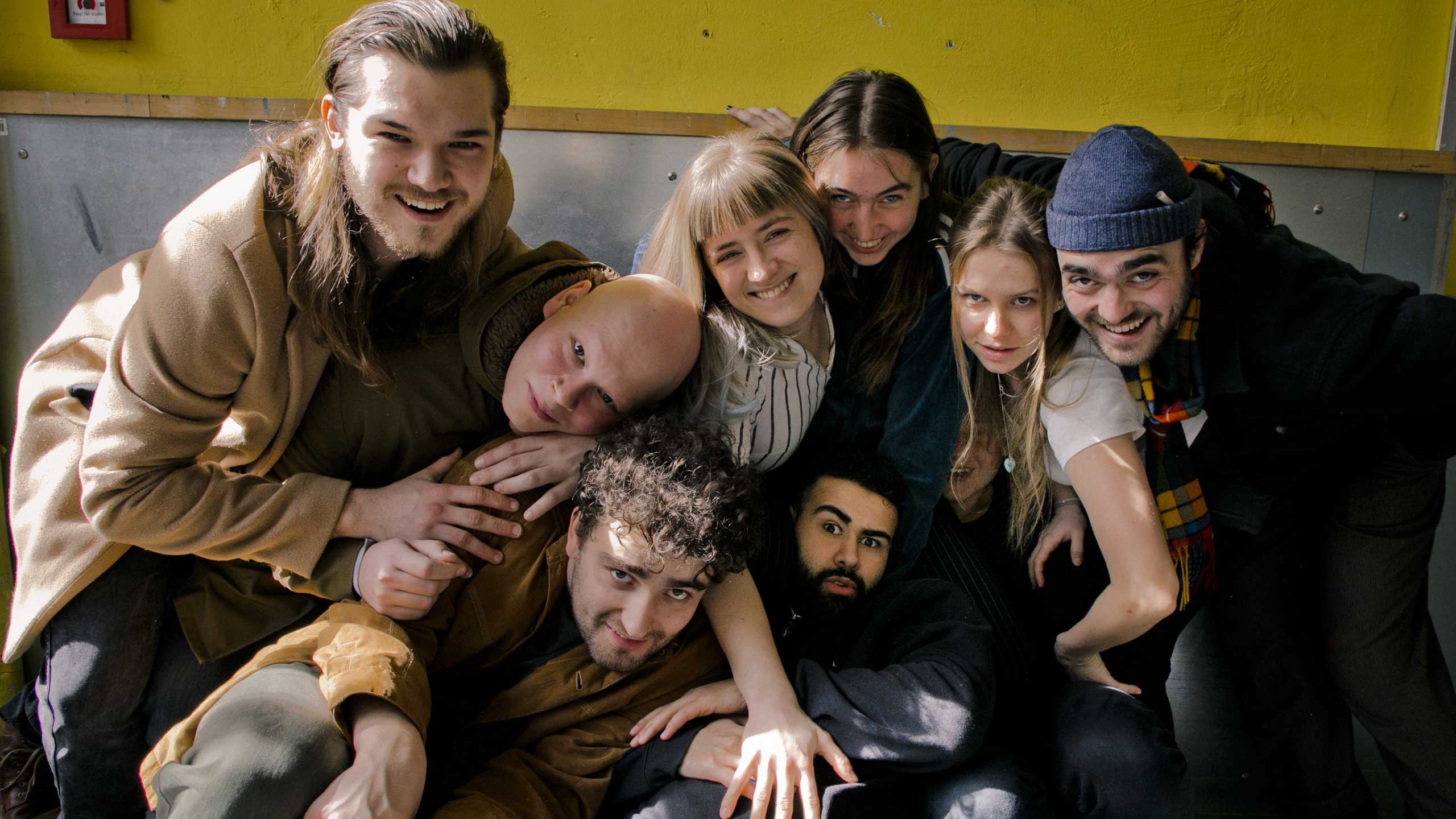 Lässiges Gruppenfoto der Studierende, die in der Kamera ungezwungen lächeln, und sich im Technischen Gang der Bayerischen Theaterakademie befinden. Dabei sind von L. nach R.: John Ragner, Hannes Tillian, Florian Lange , Daria Welsch, Frieda Lüttringhaus, Ilias Ouadi, Hanna Moreth und Finn-Morten Schuy