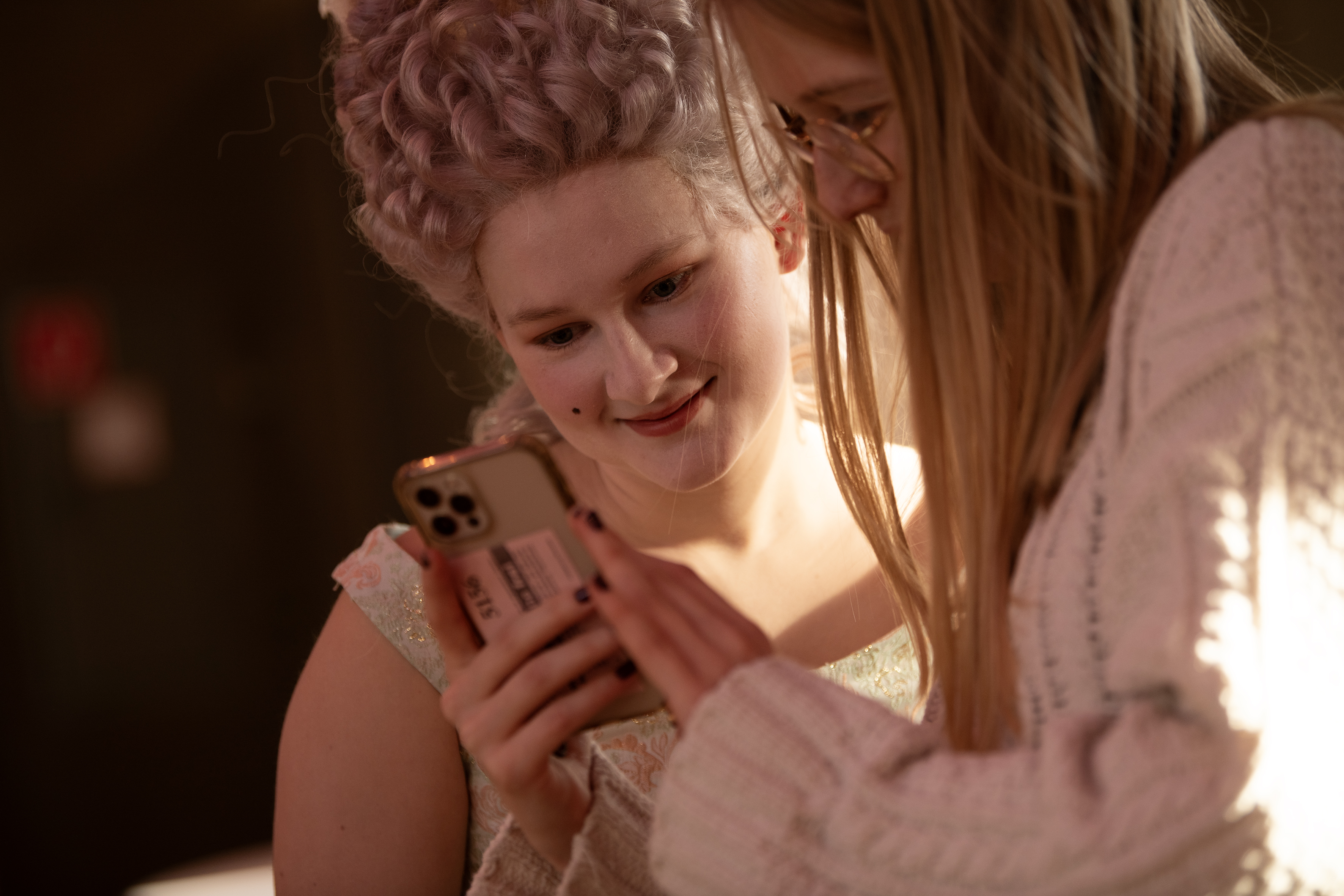 Eine mittelalterlich geschminkte Frau schaut mit einer anderen Frau auf ein Smartphone