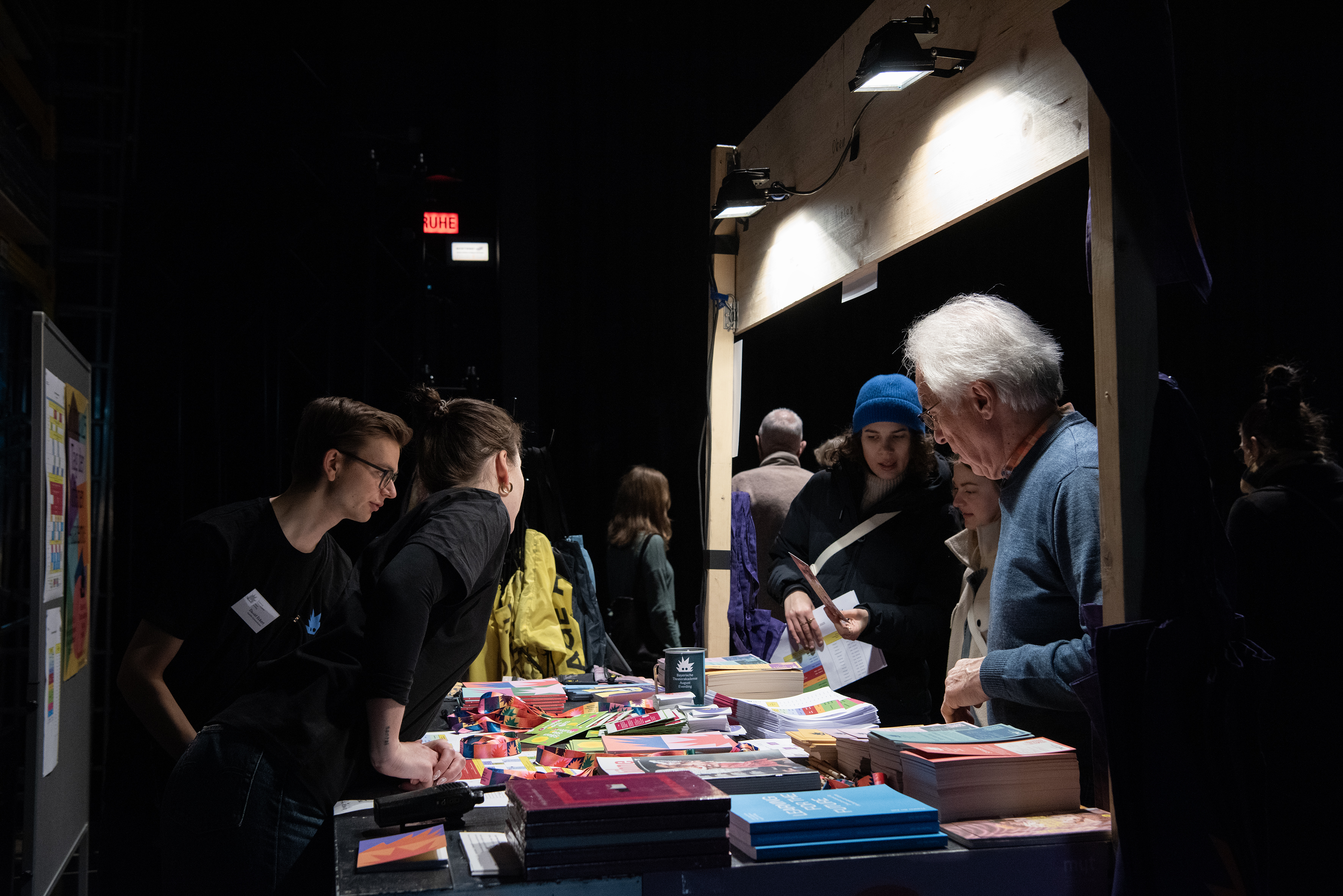 Ein Informationsstand, zwei Menschen schauen sich das ausgelegte Material an, zwei Menschen stehen hinter dem Stand zur Betreuung